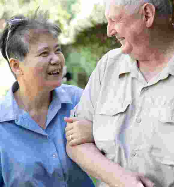 Two people outside looking at each other. One is holding the other at the elbow.