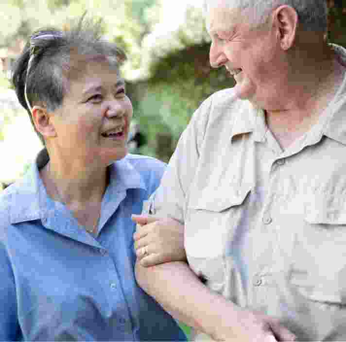 Two people outside looking at each other. One is holding the other at the elbow.