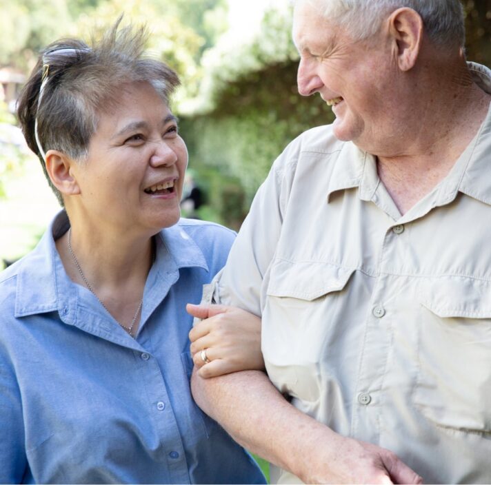 Two people outside looking at each other. One is holding the other at the elbow.