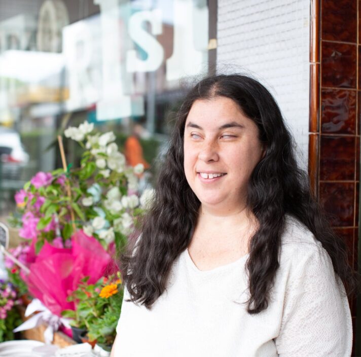 A person standing outside a flower shop with a smile on their face.