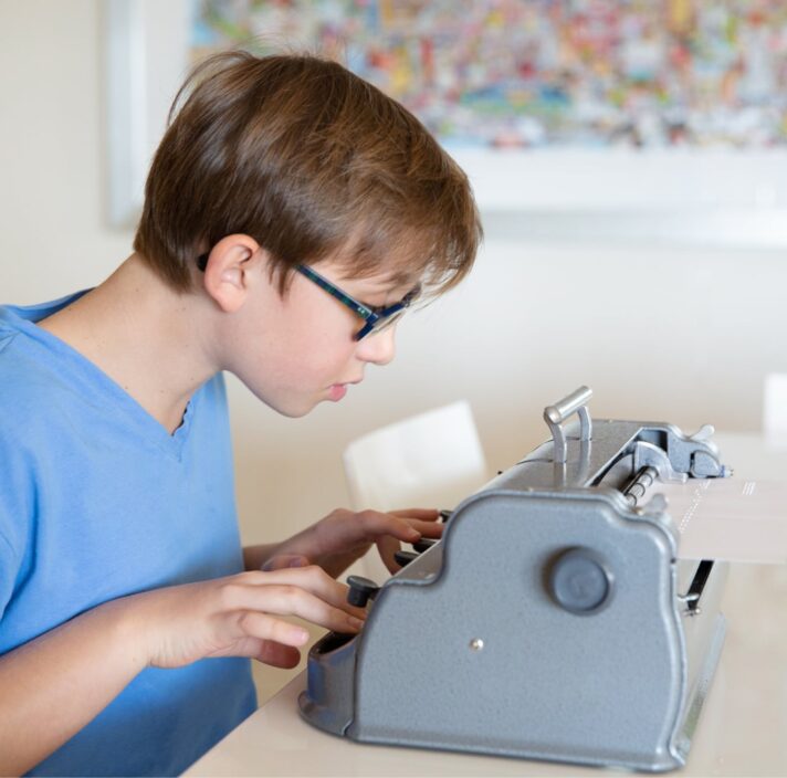 A young child using a braille machine.