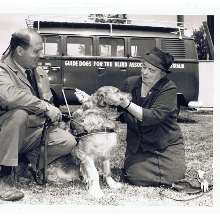 A black and white photo of Lady Coles and Tom Blair sitting with a yellow Labrador