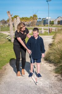A Guide Dogs staff member assists a child using a white cane