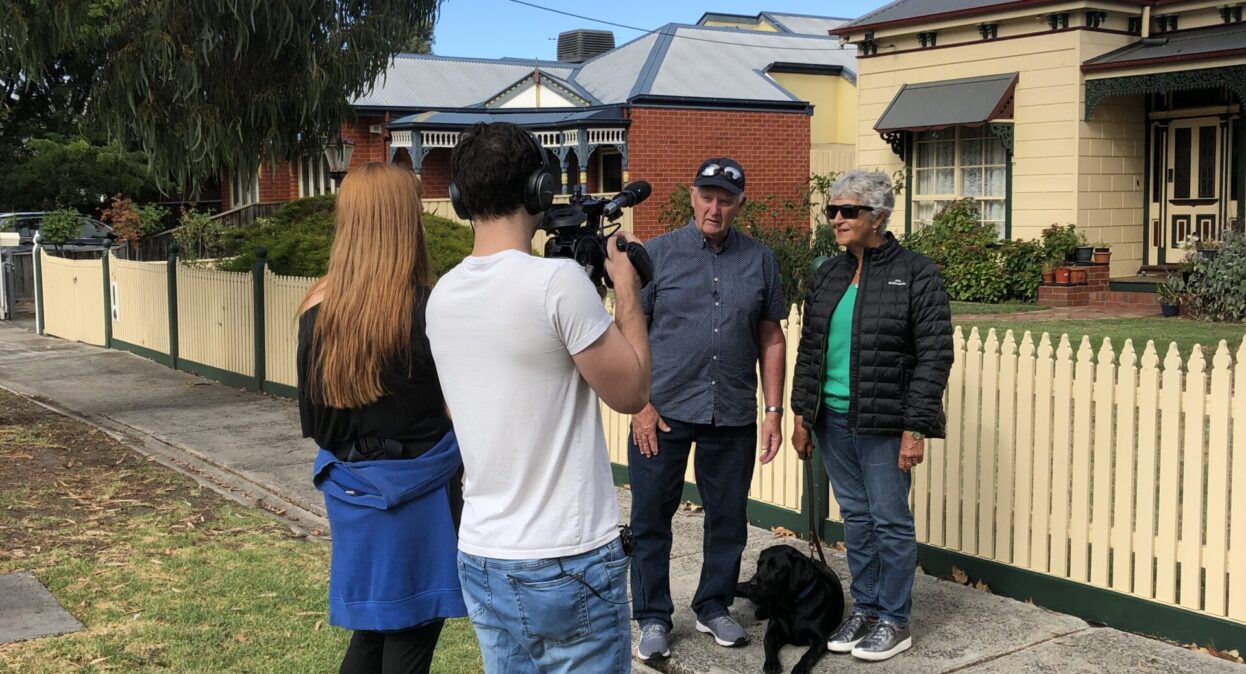 Two people filming outside a house