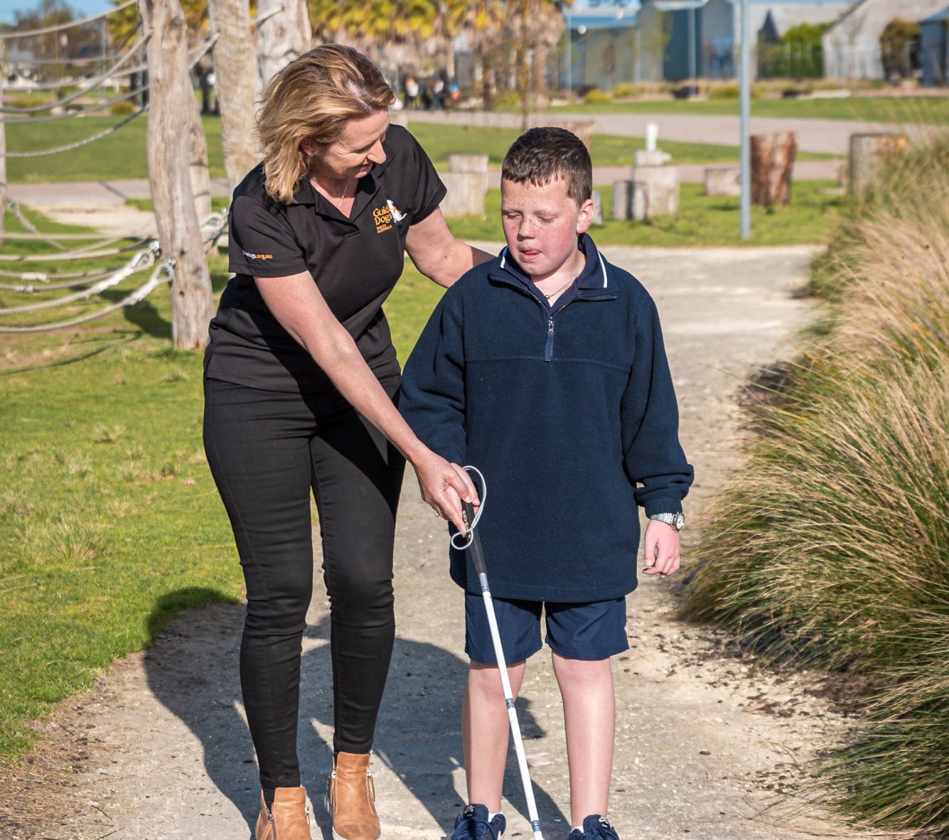 A Guide Dogs staff member assists a child using a white cane