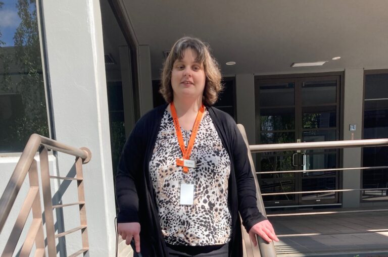A person with a long cane walking down a set of stairs.