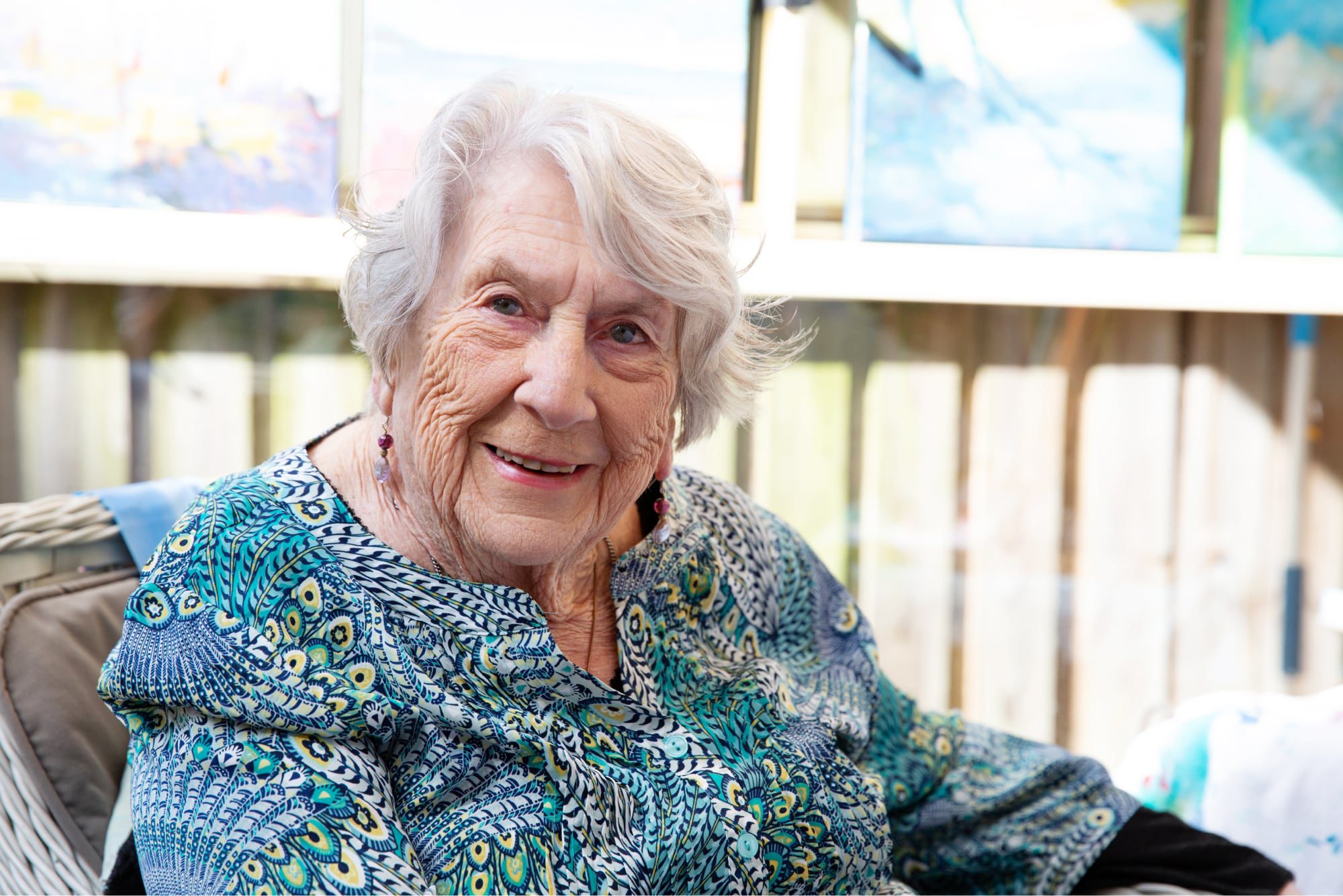 An older adult sitting in a chair smiling at the camera.