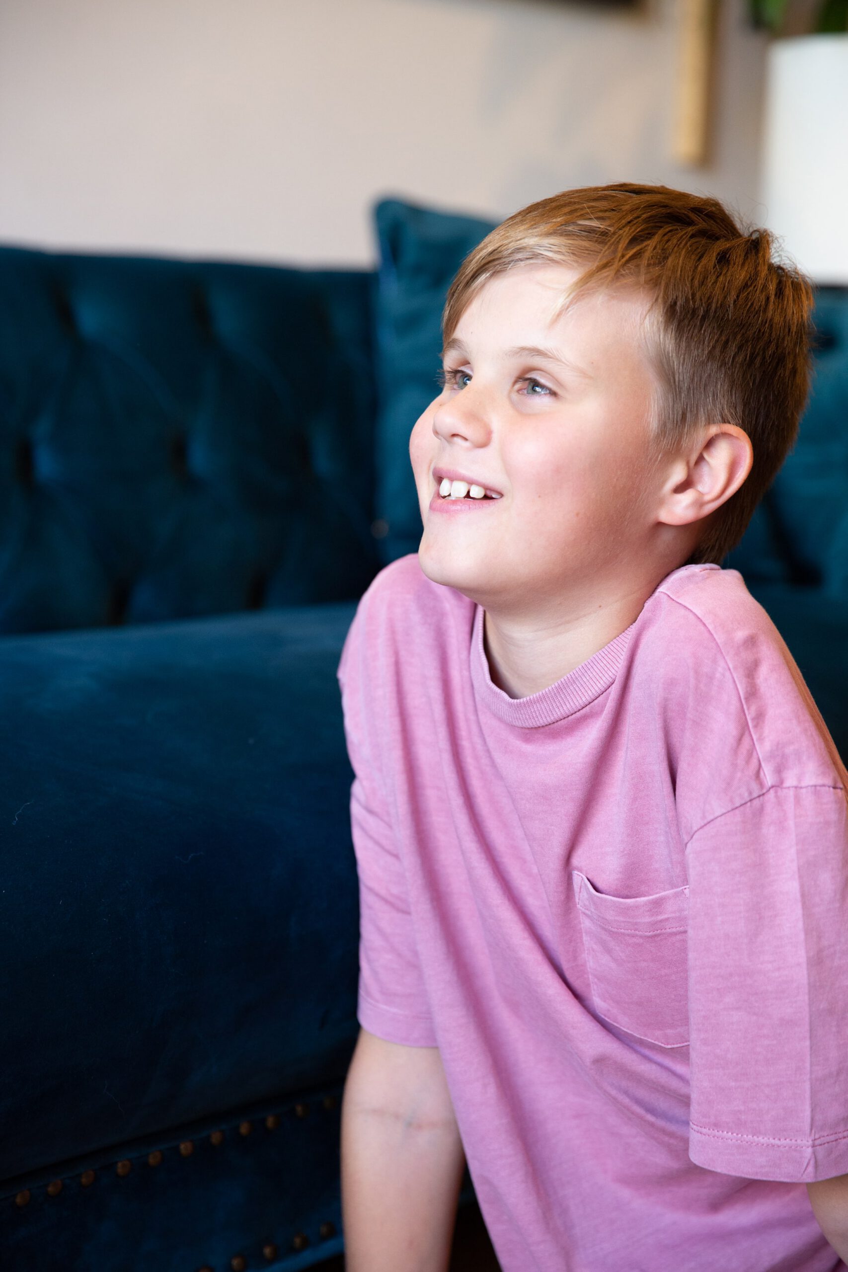A boy sitting in a living room, smiling