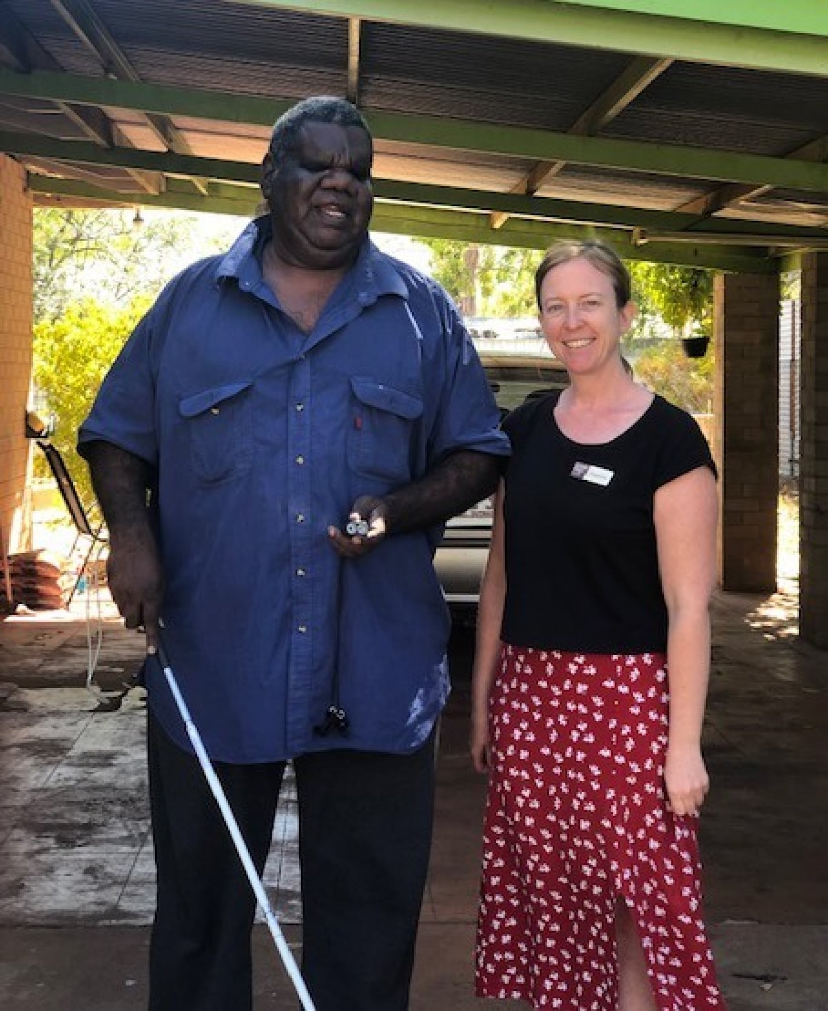 Two people standing outside lookin at the camera smiling.